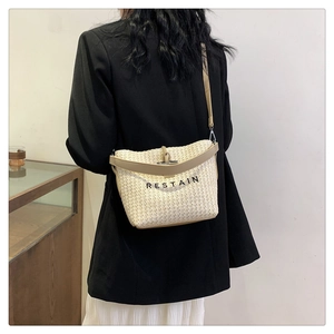 Détail du sac à bandoulière tissé crème avec broderie RESTAIN noire et lanières en cuir