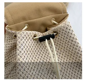 Close-up of woven straw texture with white cotton drawstring and gold metal eyelets