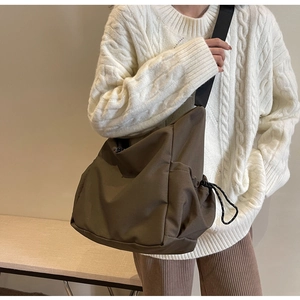 Detail of a dark brown slouchy canvas crossbody bag with adjustable wide shoulder straps