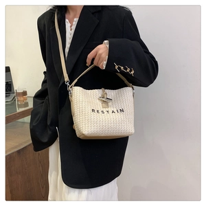 Détail d'un sac seau tissé avec bandoulière en cuir et logo RESTAIN en gros plan
