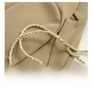 Detail showing the beige woven shoulder strap with intricate spiral texture and design