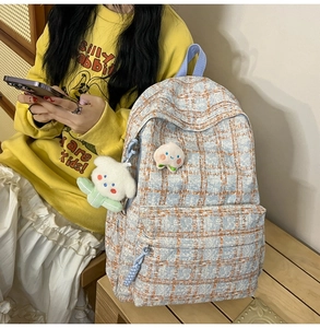 Detail of plaid corduroy backpack featuring a cute teddy bear charm and peach patch