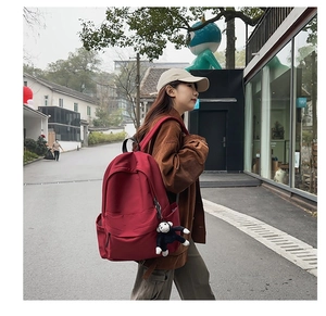 Close-up of red nylon fashion backpack with cute plush monkey pendant charm in outdoor street