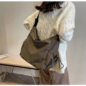 Detail of a large brown canvas hobo bag with drawstring closure worn by a model