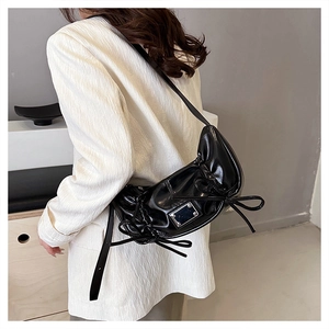 Détail du sac à bandoulière en cuir PU brillant noir avec design plissé et décoration nœud