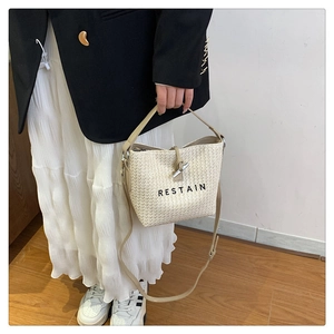 Détail du sac seau tressé crème avec cordon en cuir et fermoir à bascule en corne métal