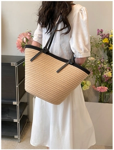 Détail d'un sac cabas en paille tressée avec bordure noire et bandoulière à nœud élégante