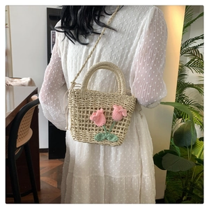Detail of handmade straw bag with pink crochet tulips and adjustable crossbody strap