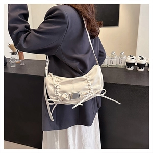 Gros plan sur un sac bandoulière en similicuir crème avec détails froncés et nœud décoratif