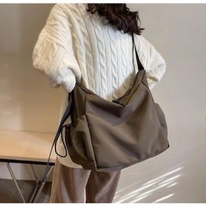 Detail view of brown canvas crossbody bag with drawstring pocket and adjustable strap