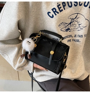 Close-up of black PU leather crossbody bag with gold lock and plush monster charm detail