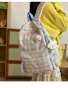 Close-up of blue and orange checkered corduroy backpack with cute plush charms