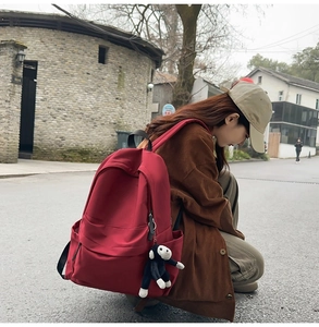 Outdoor street shot of a red nylon backpack with a monkey plush keychain charm