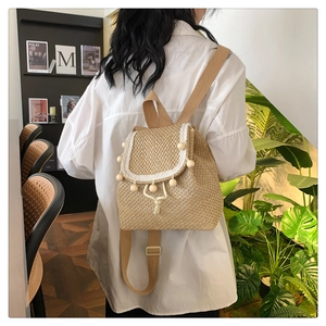 Rear view of model wearing a woven straw backpack with wooden beads and white trim detail