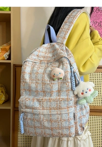 Close-up of corduroy backpack with peach embroidery and fluffy white puppy pendant