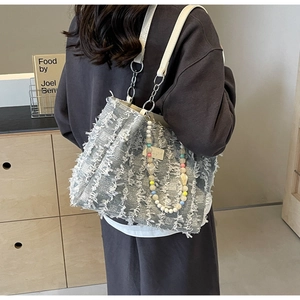 Detail der blau-grauen Fransen-Stofftasche mit weißem Lederriemen und bunter Perlenverzierung