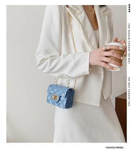 Détail du mini sac bleu matelassé avec poignée en perles et chaîne dorée sur mannequin