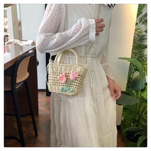 Straw woven tote bag featuring crochet pink tulips shown on model with white dress