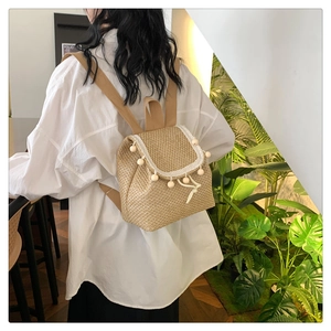 Close-up of woven straw backpack with white lace trim and wooden bead details