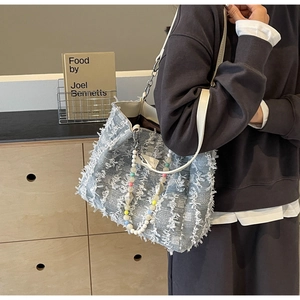 Detail der blauen Tweed-Tasche mit Fransen, Lederriemen und bunten Perlenanhängern
