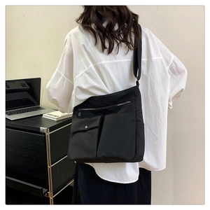 Dettaglio della borsa a tracolla in nylon nero con doppie tasche frontali e tracolla