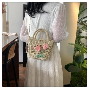 Detail of hand-woven straw bag featuring pink crochet tulips and green leaves decoration