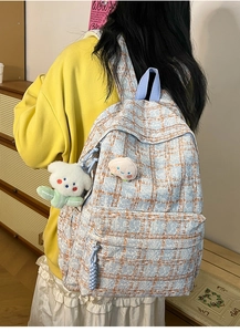 Detail of plaid corduroy backpack with cute bear pendant and cartoon patch on front pocket