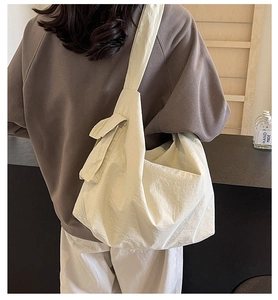 Detailed back view of a cream nylon crossbody bag with wide strap and side pocket