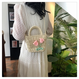 Detail of hand-woven straw bag featuring 3D pink crochet tulips and drawstring liner