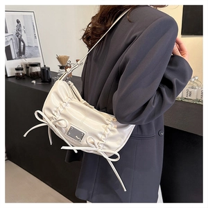 Détail du sac à épaule en similicuir crème avec nœuds décoratifs sur un mannequin
