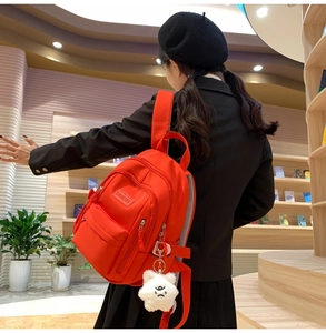 Detail of orange casual backpack with multi-zipper pockets and star plush charm accessory