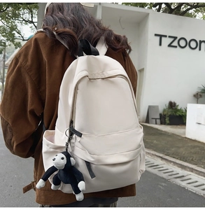 Detailed close-up of off-white nylon backpack featuring a cute long-armed monkey charm