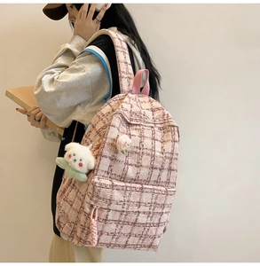 Detailed side view of pink plaid backpack with plush pendant and decorative badges