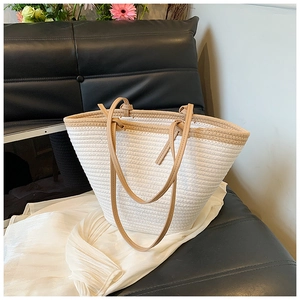 Sac fourre-tout tissé blanc minimaliste avec poignées en cuir marron sur canapé noir