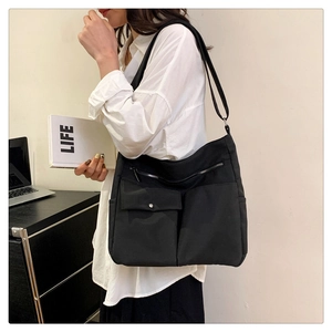 Borsa tote alla moda in nylon nero indossata da modella con tasche anteriori funzionali