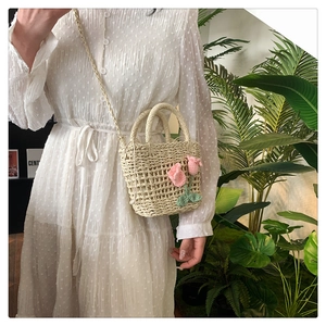 Detail of hand-woven straw shoulder bag featuring pink crochet tulip flowers and strap