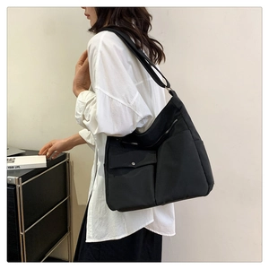 Vista laterale di una borsa tote nera in tessuto oxford capiente indossata da modella