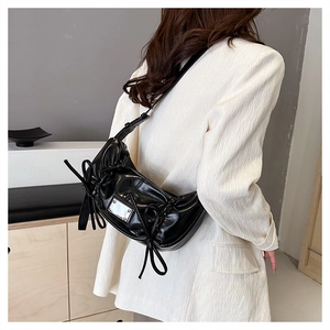Vue de côté du sac porté épaule en cuir verni noir brillant avec détails de nœuds