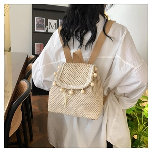 Detailed view of woven straw backpack with wooden bead accents and khaki straps