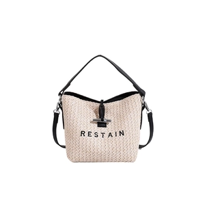 Minimalist beige woven straw bucket bag with black leather handle and RESTAIN embroidery