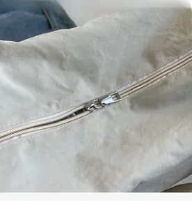Close-up of smooth silver metal zipper on minimalist nylon crossbody bag for women