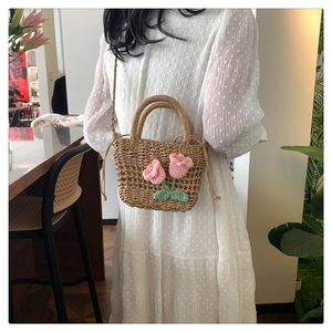 Detail of straw handbag with knitted pink tulips worn as a cross-body bag