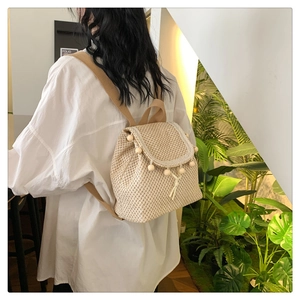 Detailed close-up of beige woven texture with light wooden beads on a stylish backpack