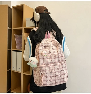 Detail view of pink plaid corduroy backpack texture with cute lamb and peach plush charms