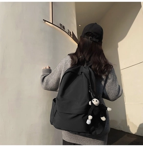 Fashionable black nylon backpack for women with a cute plush monkey keychain detail