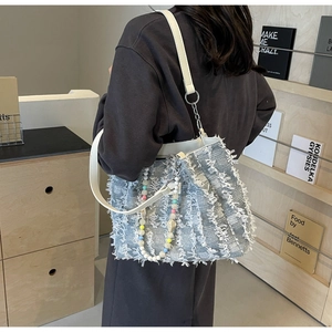 Detailansicht hellblaue Tweed-Tasche mit Fransenstruktur und Perlen-Schultergurt
