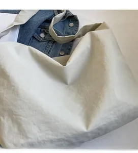 Detail view of lightweight off-white nylon tote bag with soft texture and slim shoulder strap