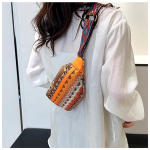 Close-up of bohemian embroidered belt bag with colorful geometric strap on white shirt