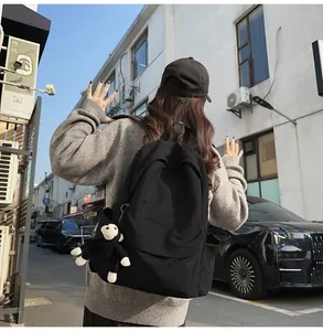 Street view of black nylon backpack featuring a cute monkey keychain and side pockets