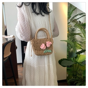 Detail of straw woven bag with crochet pink flowers and green leaves pattern